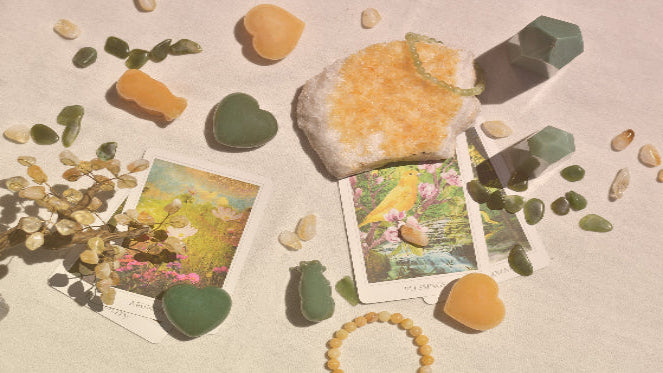 Decorative arrangement with stones, a bracelet, and oracle cards on a textured surface.