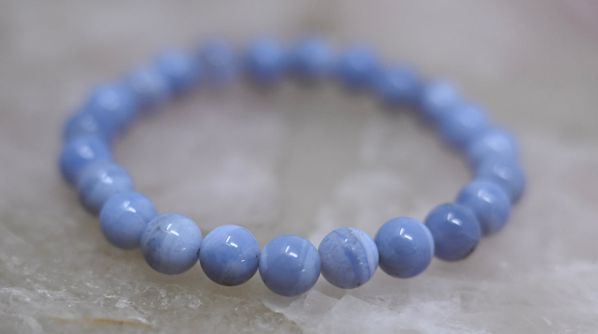 Close-up of the blue lace agate bracelet showing pale-blue round beads with white bands and natural markings.